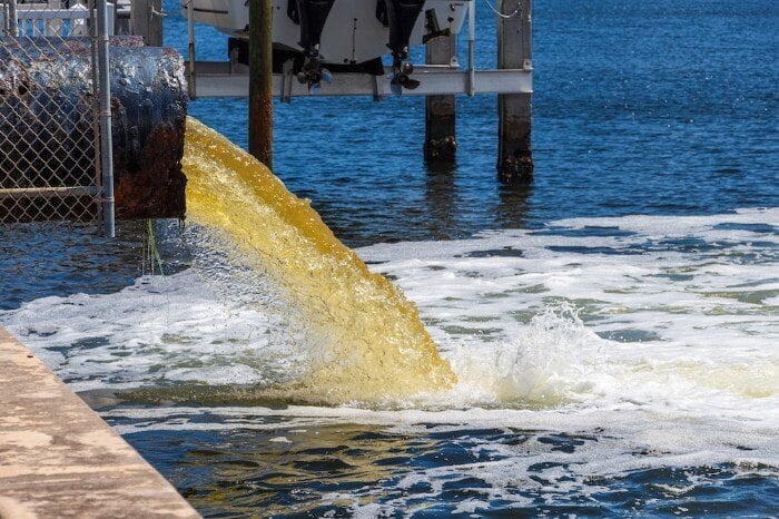 Wastewater flowing out of a pipe into a river