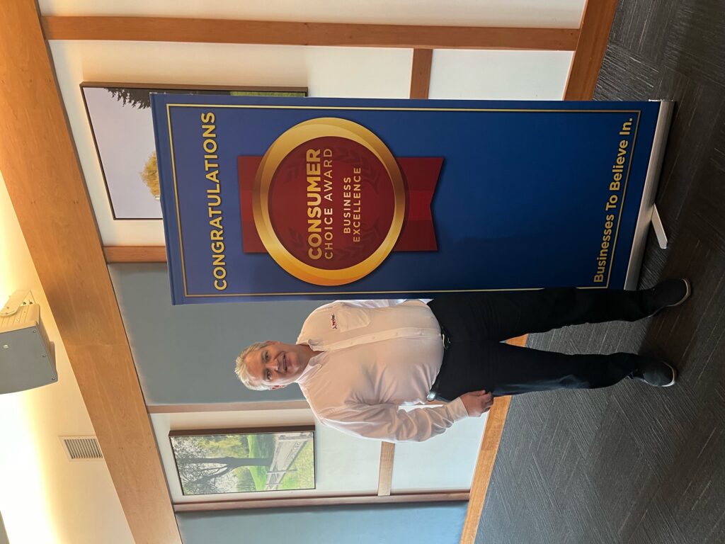 PuroClean of Nanaimo owner Jason Ness poses in front of Consumer Choice Award banner