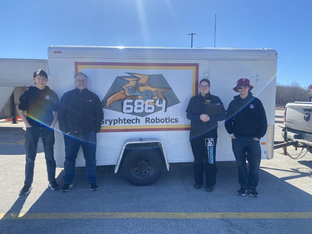 The Gryphtech Robotics team is standing before their newly detailed equipment trailer.