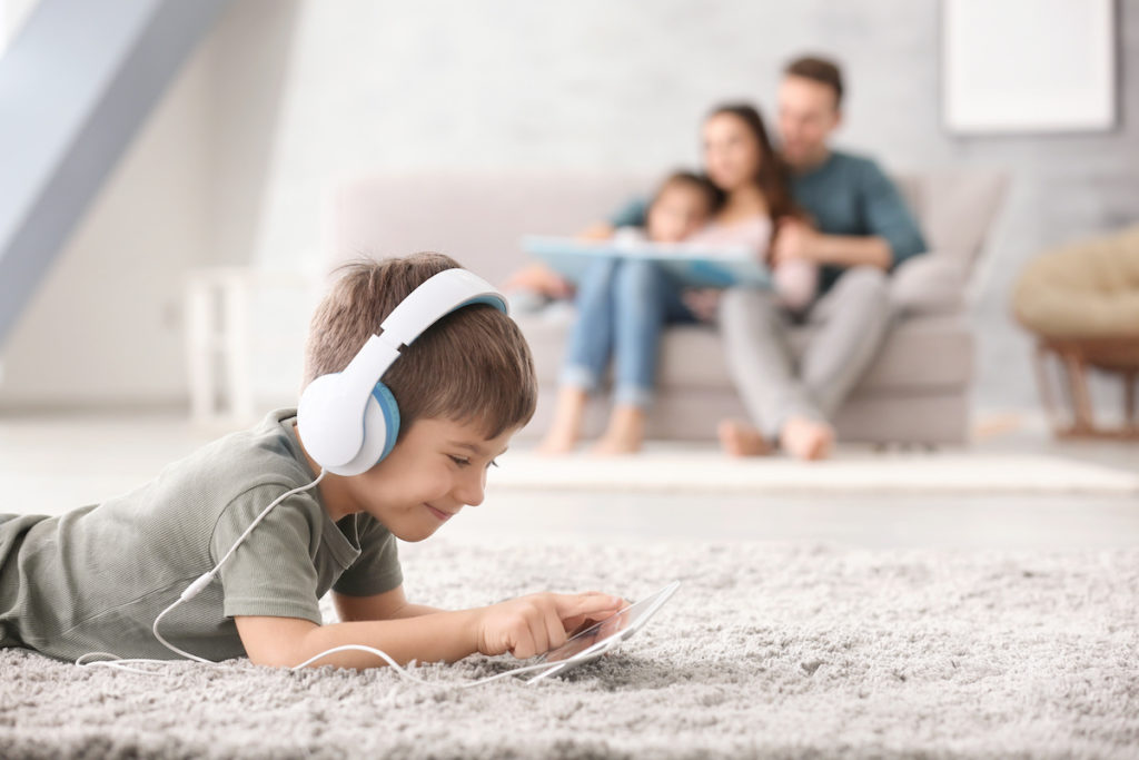 A kid listening to music lying on a clean carpet