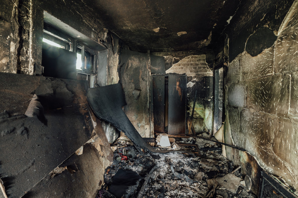 The inside of a burnt apartment is tarnished in black soot.

