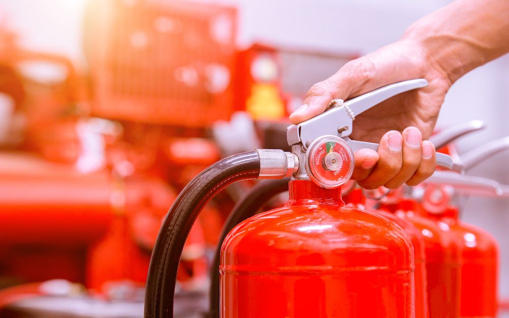 A hand grabs onto the top of a fire extinguisher. 