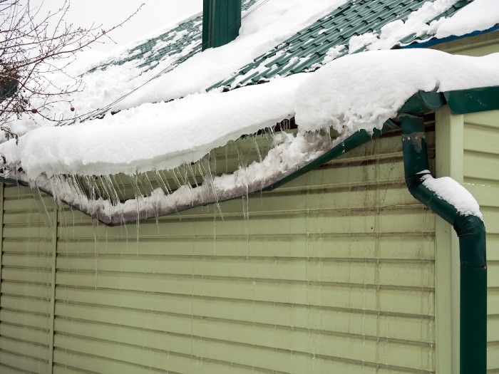 A gutter on a roof being weighed down by an ice dam